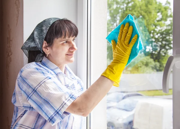 Mujer limpiando una ventana con un trapo — Foto de Stock