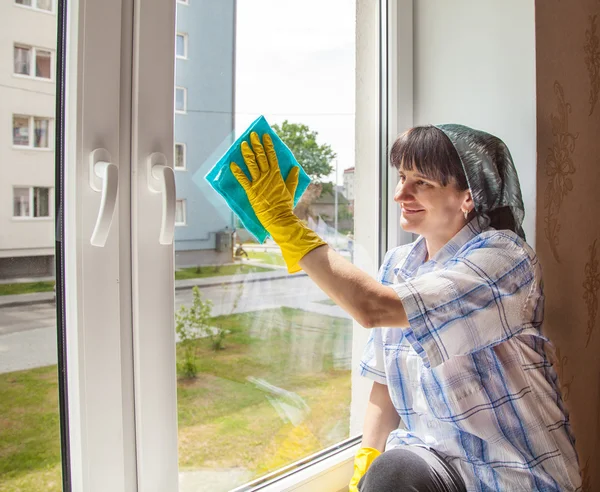 Joven sonriente mujer lava una ventana — Foto de Stock