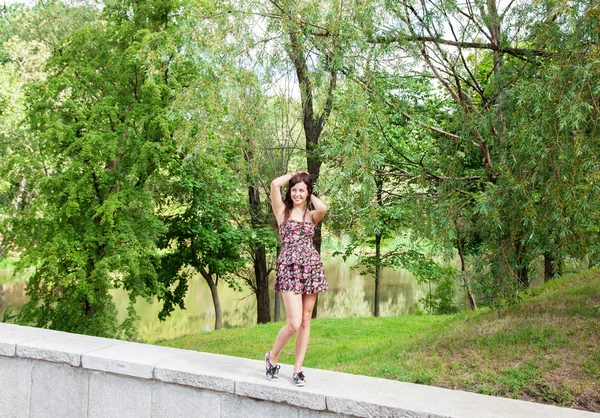 Jovem bela menina sorridente posando enquanto de pé no parque — Fotografia de Stock