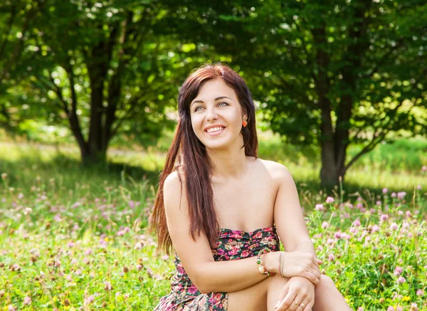 Jovem bela menina sorridente sentado na grama — Fotografia de Stock