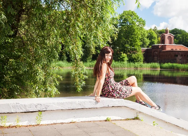 Krásná bruneta sedí blízko jezera — Stock fotografie