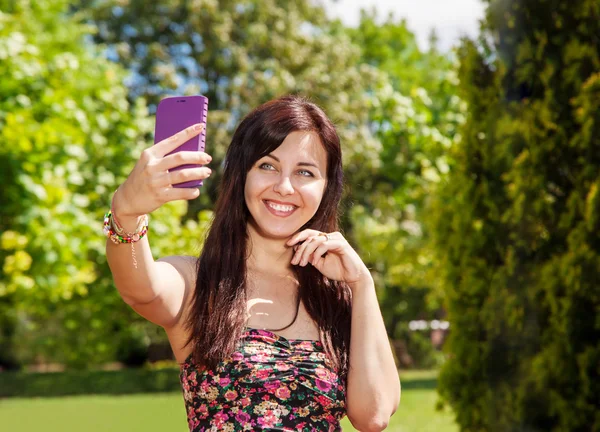 Девушка делает селфи мобильный телефон в парке — стоковое фото