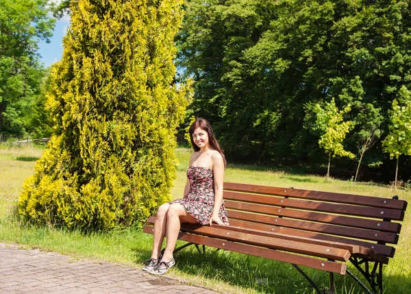 Jovem mulher sentada em um banco de parque — Fotografia de Stock