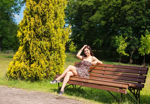 Jovem sentada em um banco de parque — Fotografia de Stock