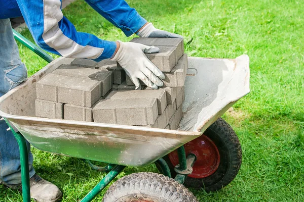 Worker puts paving stabs tile in a wheelbarrow — Stock Photo, Image