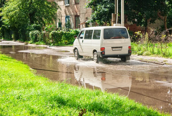 Minibus jazda na kałuży na drodze — Zdjęcie stockowe