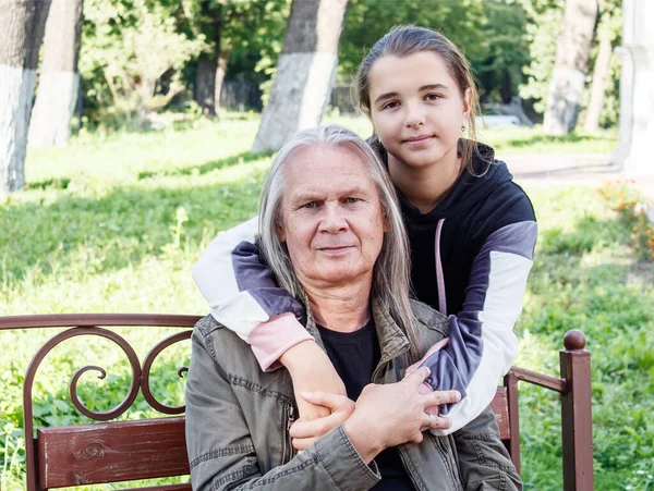 Wnuczka Przytula Dziadka Ławce Parku Miejskim Słoneczny Jesienny Dzień — Zdjęcie stockowe