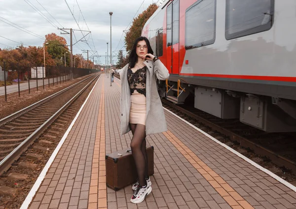 Kasvetli bir sonbahar gününde tren istasyonunda bavullu yalnız bir genç kız.