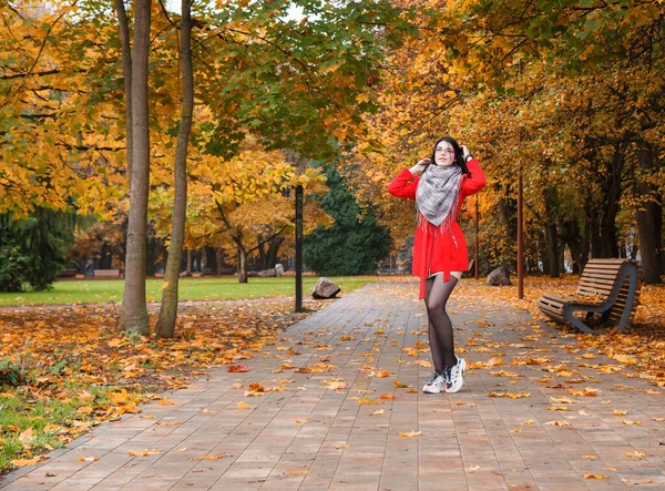 秋の日に公園の路地に立つ赤いコートの少女 — ストック写真