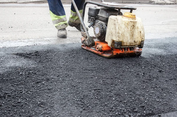 作業員は道路のアスファルトを機械式のラマーで滑らせます 道路の表面を敷設 ラマーの圧力で熱いアスファルトが — ストック写真