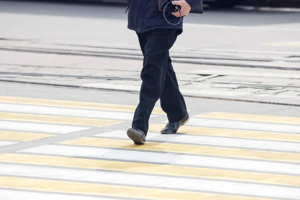 pedestrians cross the street at a pedestrian crossing on spring day