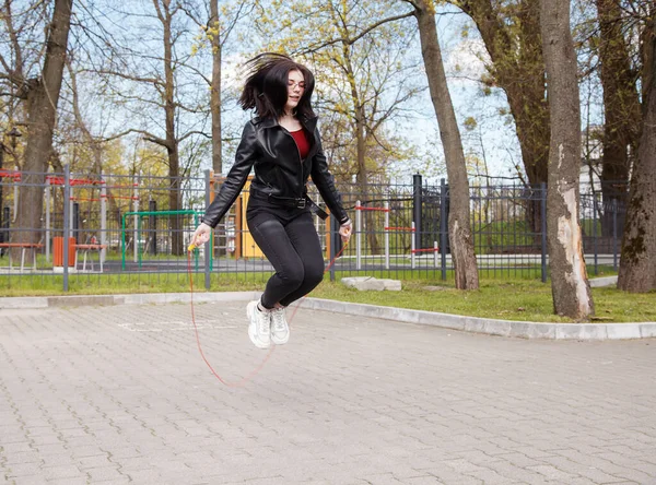 Mladá Brunetka Dívka Černé Bundě Džíny Skákací Lano Venku Slunném — Stock fotografie