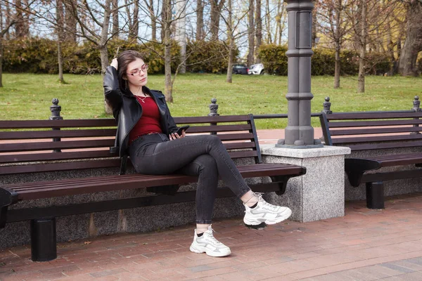 Young Girl Black Jacket Jeans Looking Smartphone Display While Sitting — Stock Photo, Image