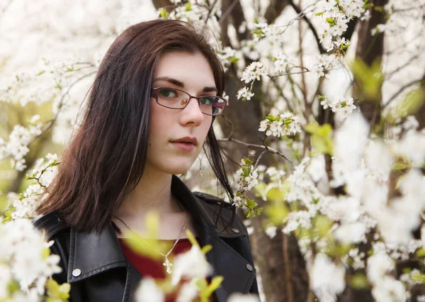 春の晴れた日に桜の近くに立って黒のジャケットとバーガンディセーターで若い美しいブルネットの女の子の肖像画 屋外の閉鎖 — ストック写真