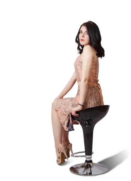 身穿米色衣服的年轻貌美的黑发姑娘坐在演播室的椅子上 背景是白色的 — 图库照片