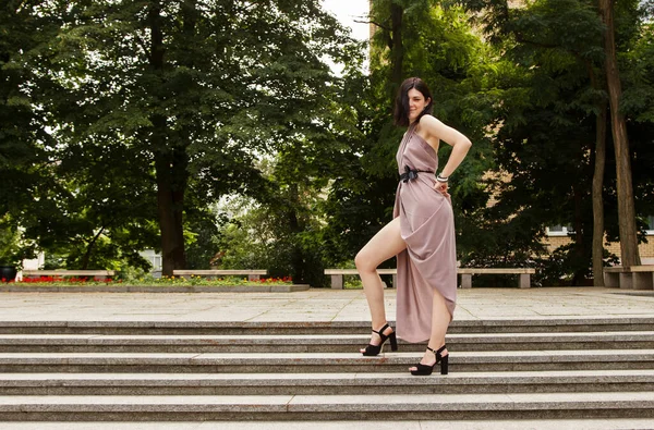 夏日阳光灿烂 身穿米色衣服的年轻漂亮的黑发女子站在城市公园的楼梯上 — 图库照片
