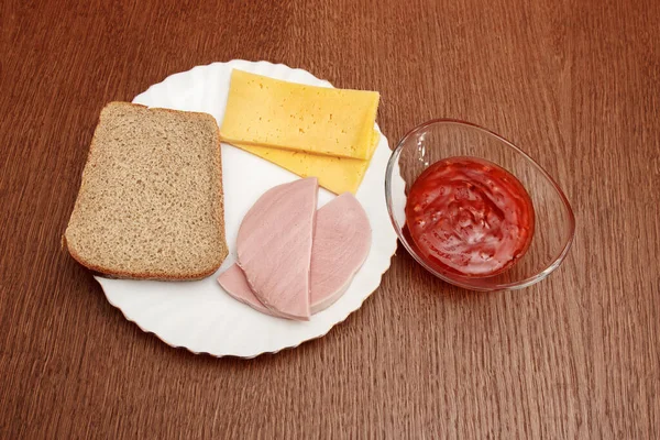 板の上にチーズパンとソーセージ 木のテーブルの上にチリソースをかけたソーサー 屋内クローズアップ — ストック写真