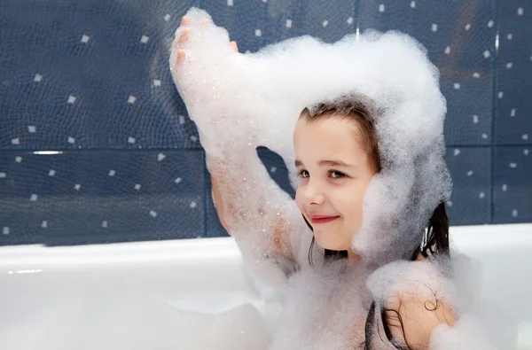 Küçük kız bir banyo oturan ve sabun köpük ile çalış — Stok fotoğraf