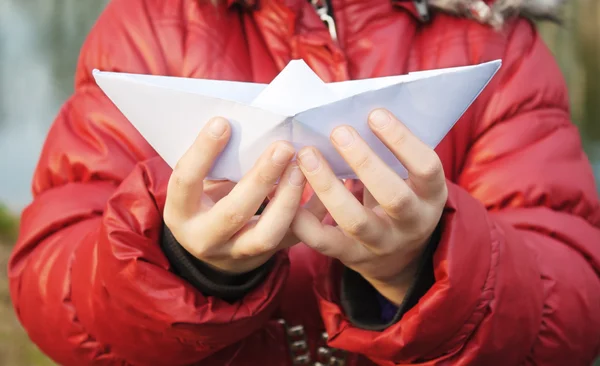 Manos sosteniendo un barco de papel de cerca fuera — Foto de Stock