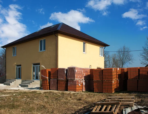 Casa nueva con pilas de ladrillos para la construcción —  Fotos de Stock