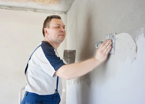 Homem de meia-idade trabalhador colocando gesso na parede — Fotografia de Stock