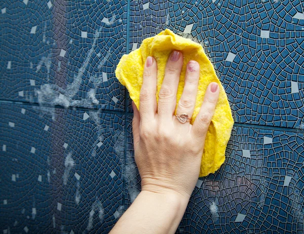 Женская рука моет десятичную плитку на стене — стоковое фото