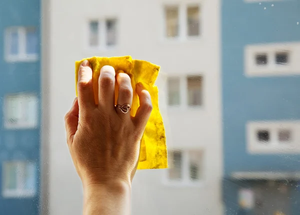 Lavando una ventana con la mano femenina — Foto de Stock