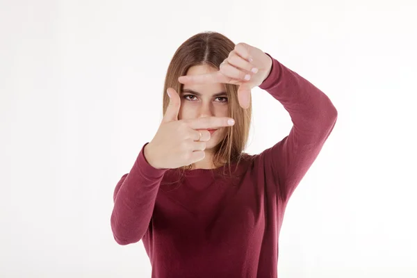 Chica mira en el marco de sus manos — Foto de Stock