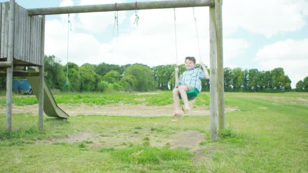 Boy having fun on playground swing — Stock Video