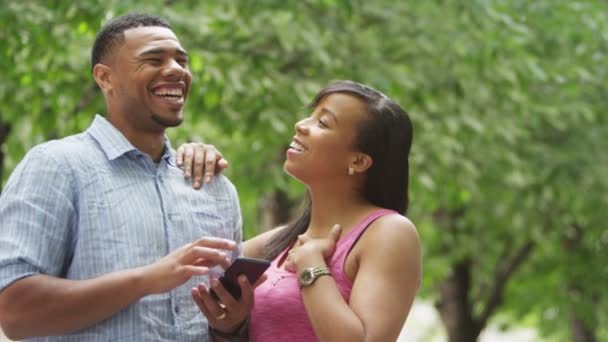 Casal de pé no parque com telefone celular — Vídeo de Stock