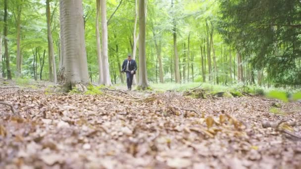 Hombre de negocios corriendo por el bosque — Vídeo de stock