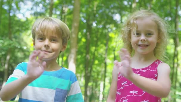 Niño y niña saludando a la cámara — Vídeo de stock