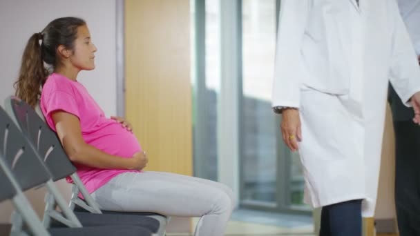 Беременная женщина сидит в зале ожидания больницы — стоковое видео