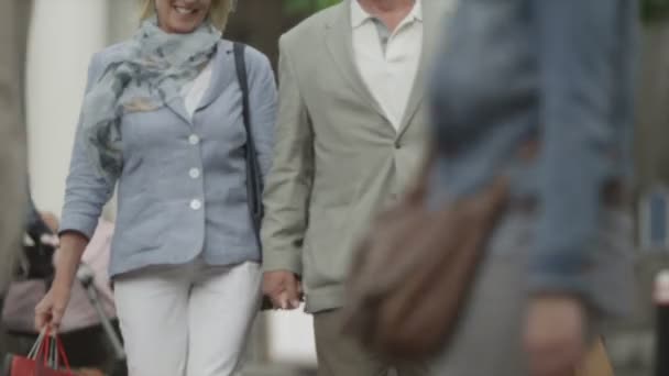 Couple avec des sacs à provisions marchant dans la ville — Video