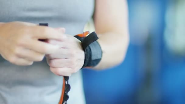 Female weightlifter putting on wrist supports — Stock Video