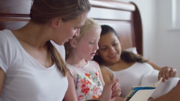 Gay female couple reading with daughter — Stock Video