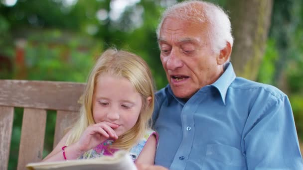 Дедушка и внучка читают вместе — стоковое видео