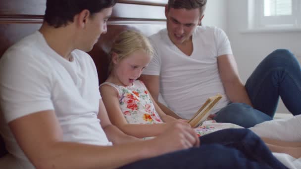 Gay couple  reading with daughter — Stock Video