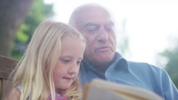 Nagyapa és unokája olvasó együtt — Stock videók