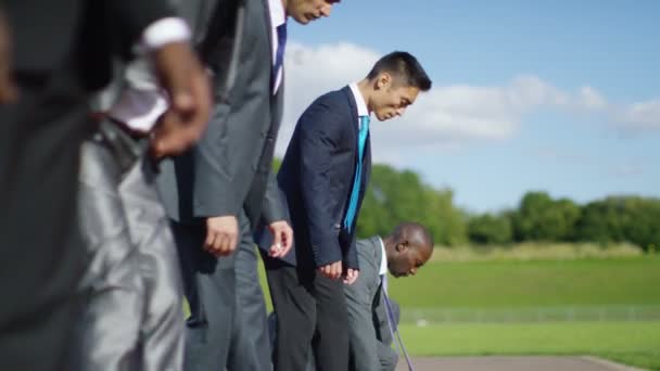 Businessmen at running track line up at starting line — Stock Video