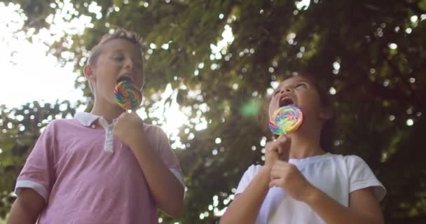 Niño y niña comiendo piruletas — Vídeos de Stock