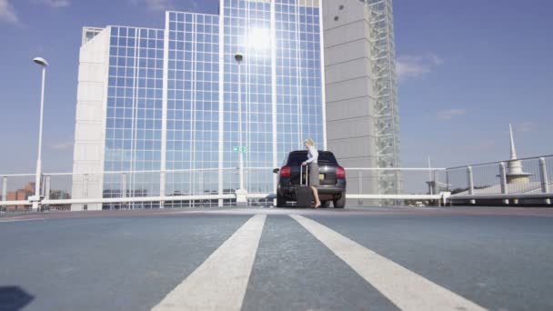 Businesswoman putting luggage into car — Stock Video