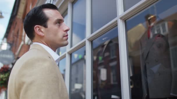 Мужчина смотрит в витрину магазина — стоковое видео