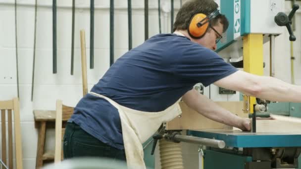 Carpintero cortando madera con una sierra de cinta — Vídeo de stock