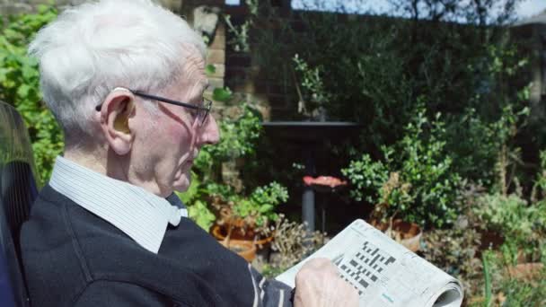 Homem idoso fazendo um quebra-cabeça de palavras cruzadas — Vídeo de Stock