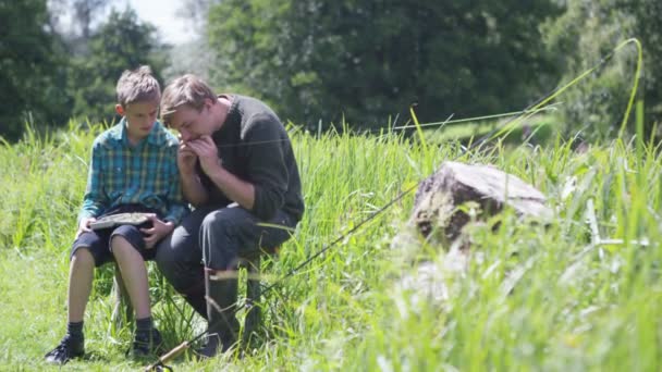 Uomo e ragazzo mettendo mosche da pesca sul gancio — Video Stock