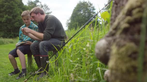 Ο άνθρωπος και το αγόρι βάζει αλιείας μύγες στο άγκιστρο — Αρχείο Βίντεο