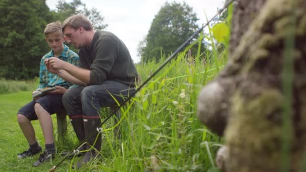 Man en jongen zetten visserij vliegt op de haak — Stockvideo