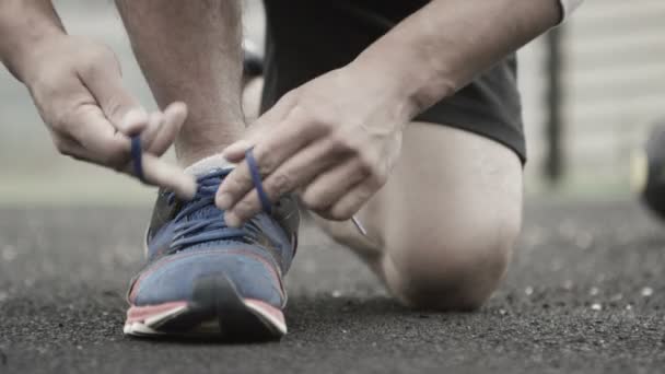 Hombre ata cordones de zapatos durante el entrenamiento — Vídeo de stock