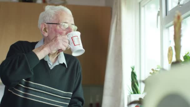 Пожилой человек пьет горячий напиток — стоковое видео